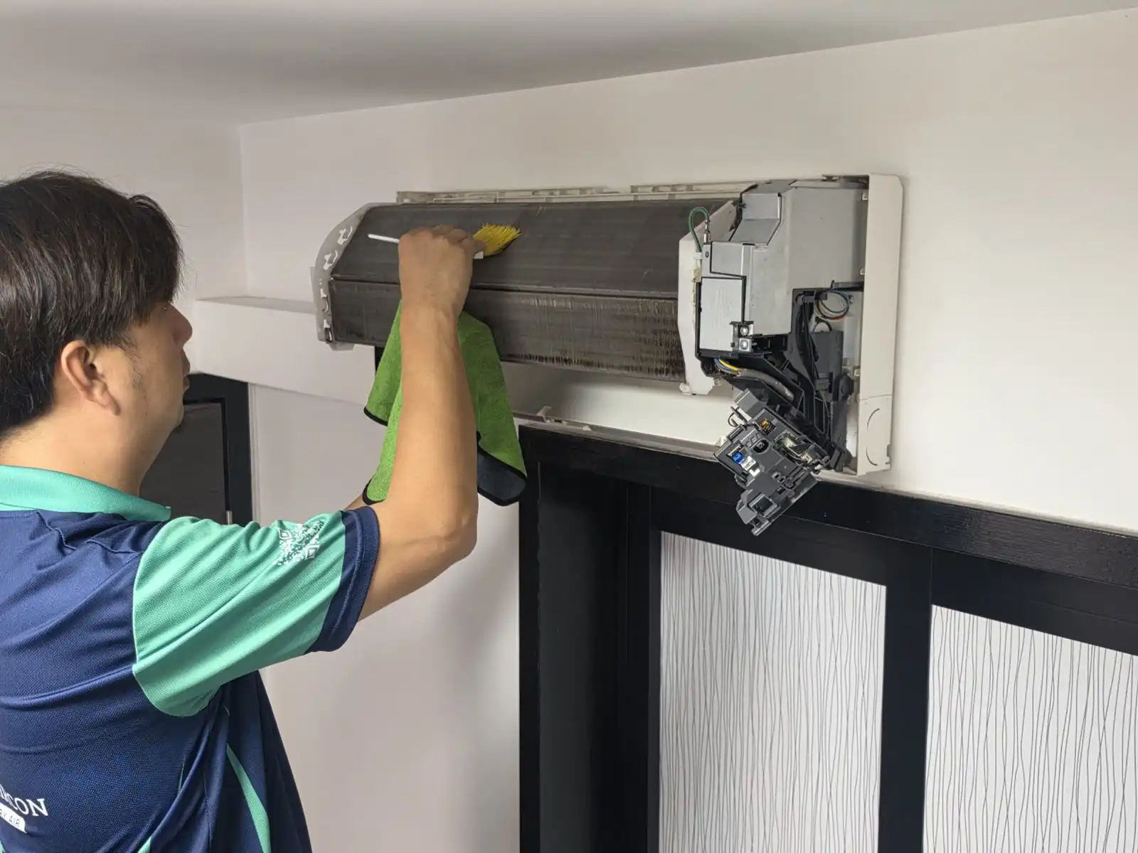 CoolTrust technician brushing and vacuuming evaporator coil